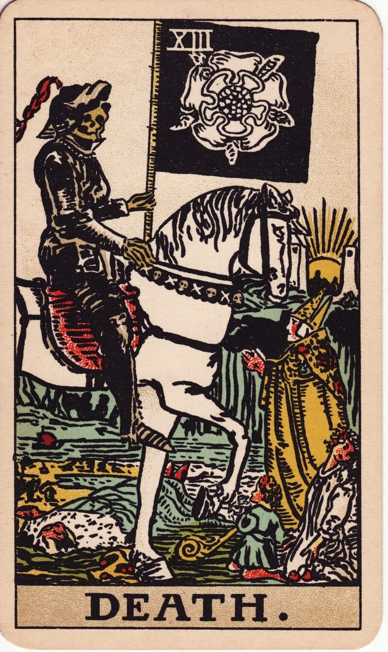 Death tarot card — skeleton in black armor on white horse carrying a banner with a white rose, Rider-Waite-Smith deck