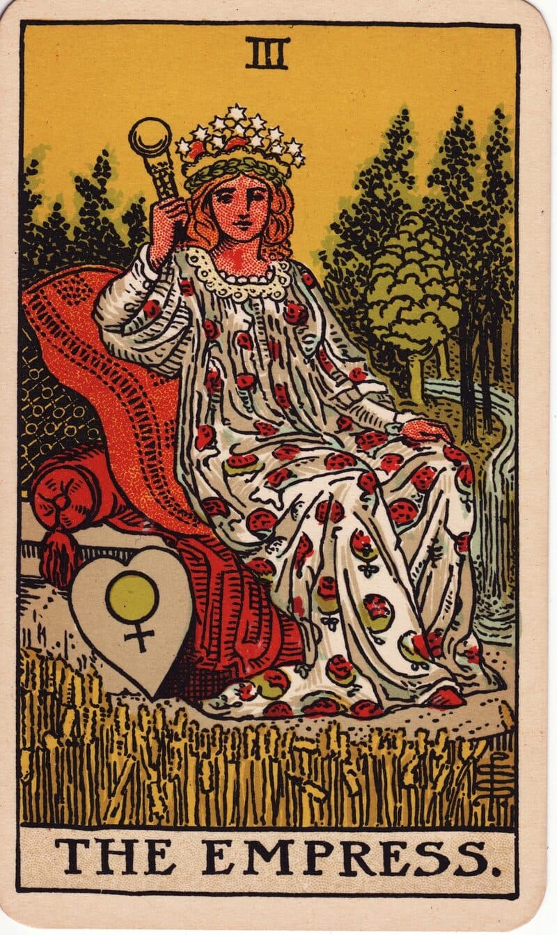 The Empress tarot card — crowned figure on cushioned throne amid wheat field with Venus shield, Rider-Waite-Smith deck