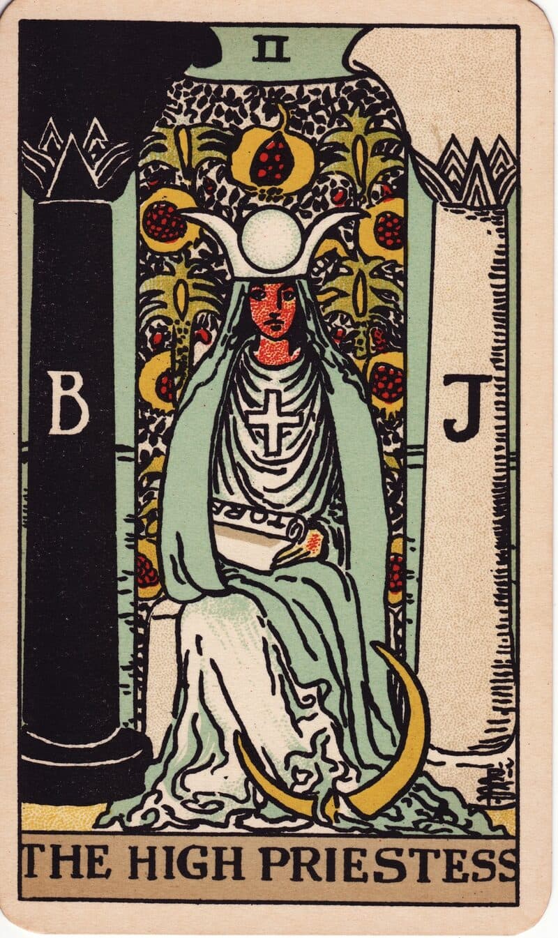 The High Priestess tarot card — seated figure between two pillars with crescent moon and pomegranate veil, Rider-Waite-Smith deck