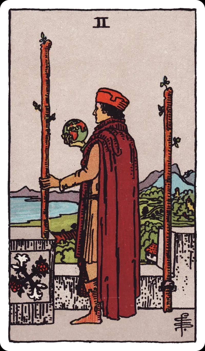 Two of Wands tarot card — cloaked figure on a castle battlement holding a small globe between two wands, gazing out to sea, Rider-Waite-Smith deck